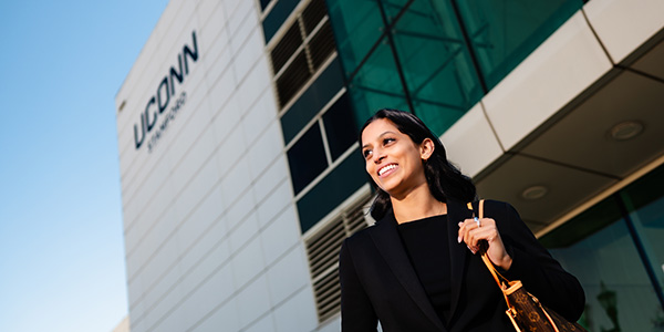 A woman stands in front of the UConn Stamford building.